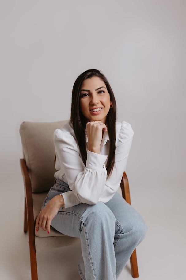Psicóloga Luísa Konorath sentada em uma poltrona, sorrindo